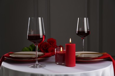 Photo of Place setting with candles and roses on white table. Romantic dinner