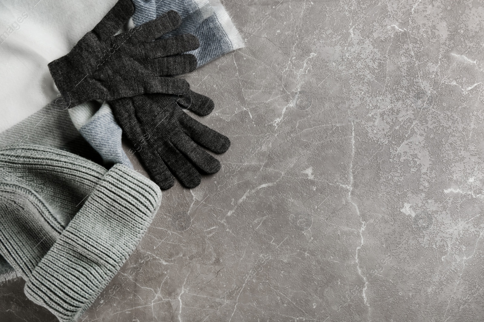 Photo of Stylish gloves, scarf and hat on light grey marble table, flat lay. Space for text