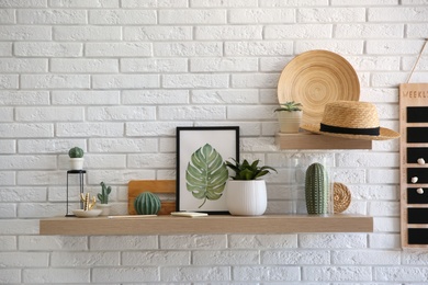 Photo of Shelves with decorative elements on white brick wall. Interior design