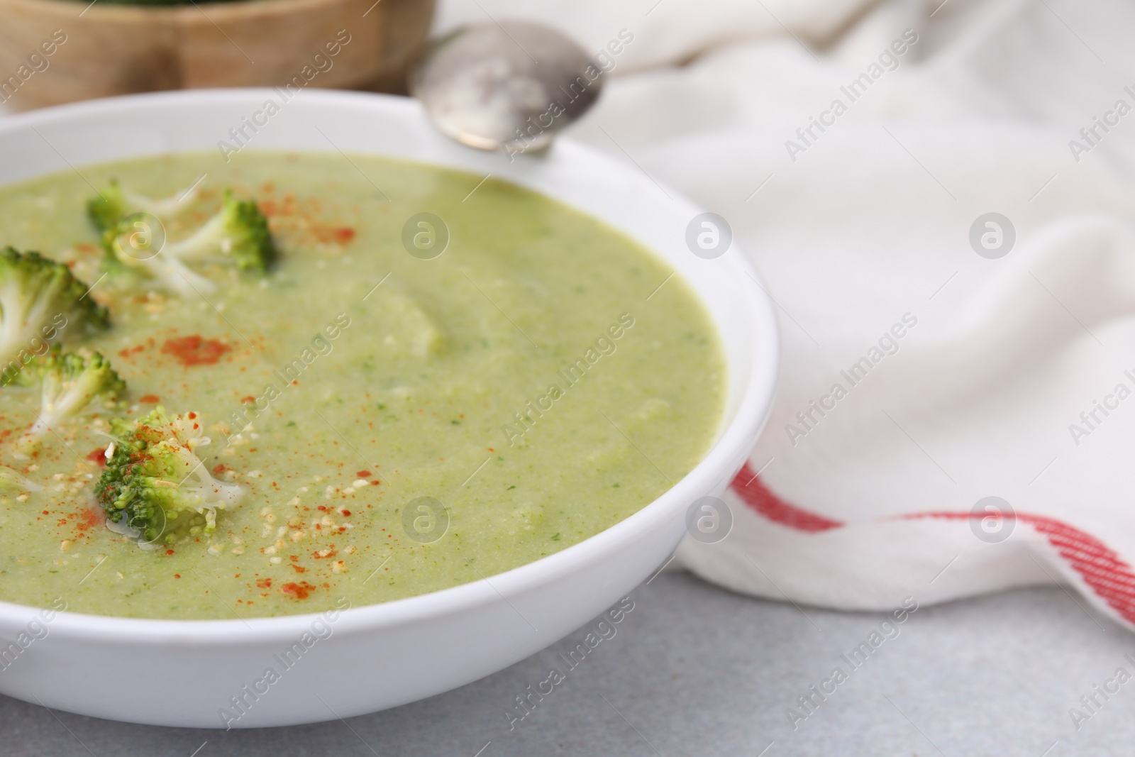 Photo of Delicious broccoli cream soup served on light table, closeup. Space for text