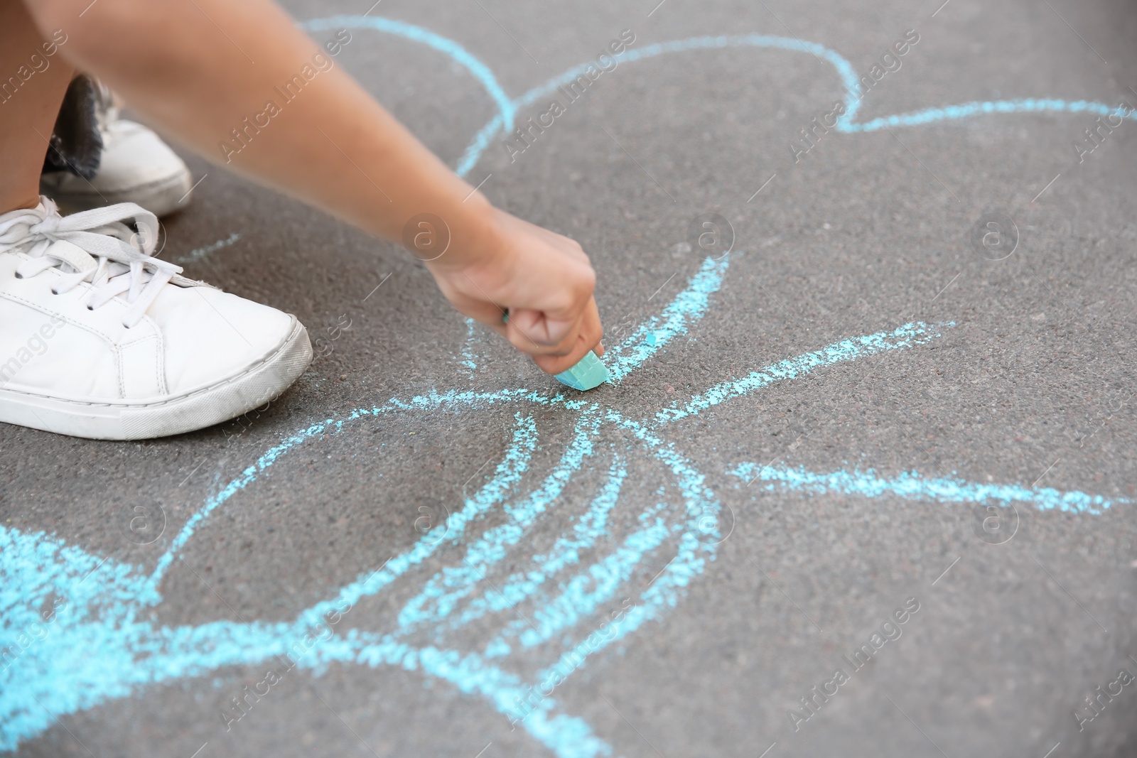 Photo of Little child drawing with chalk on asphalt, closeup