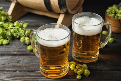 Photo of Composition with tasty beer and fresh green hops on wooden table