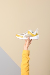 Woman holding sportive shoe on color background, closeup. Space for text