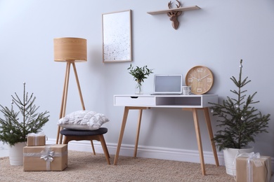 Stylish room interior with potted fir trees decorated for Christmas