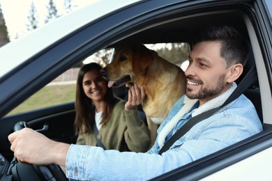 Photo of Happy couple and dog in car. Traveling with pet