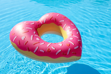 Photo of Heart shaped inflatable ring floating in swimming pool. Summer vacation