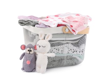 Photo of Laundry basket with baby clothes near crochet toys isolated on white