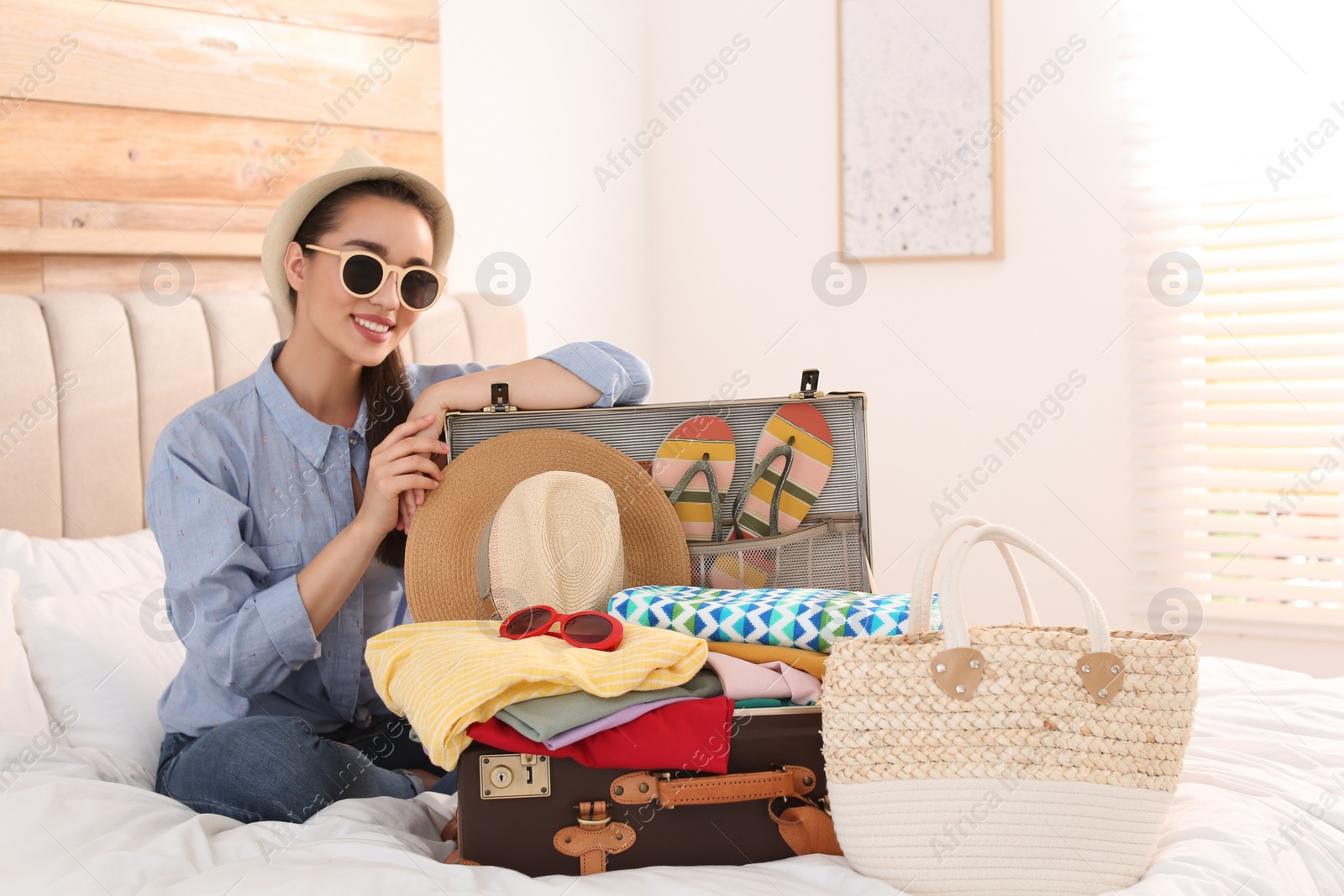 Photo of Woman packing suitcase for summer vacation in bedroom