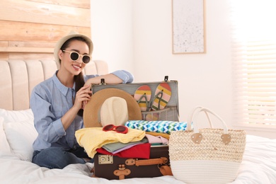 Photo of Woman packing suitcase for summer vacation in bedroom