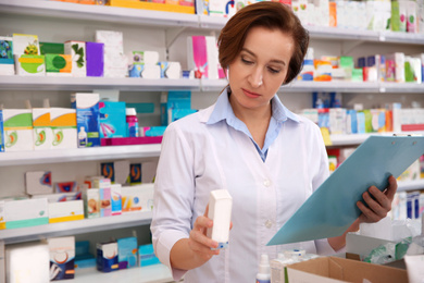 Image of Professional pharmacist with clipboard and medicine in drugstore