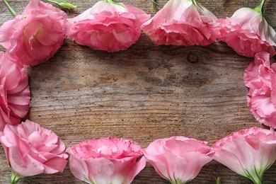 Photo of Flat lay composition with beautiful Eustoma flowers on wooden background