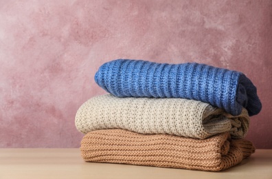 Photo of Stack of folded knitted sweaters on table. Space for text