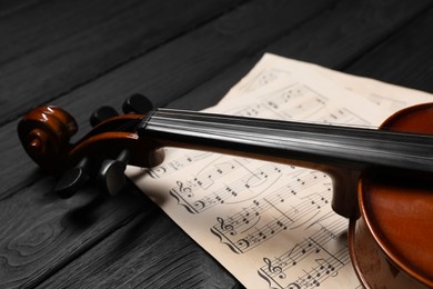 Violin and music sheets on black wooden table, closeup