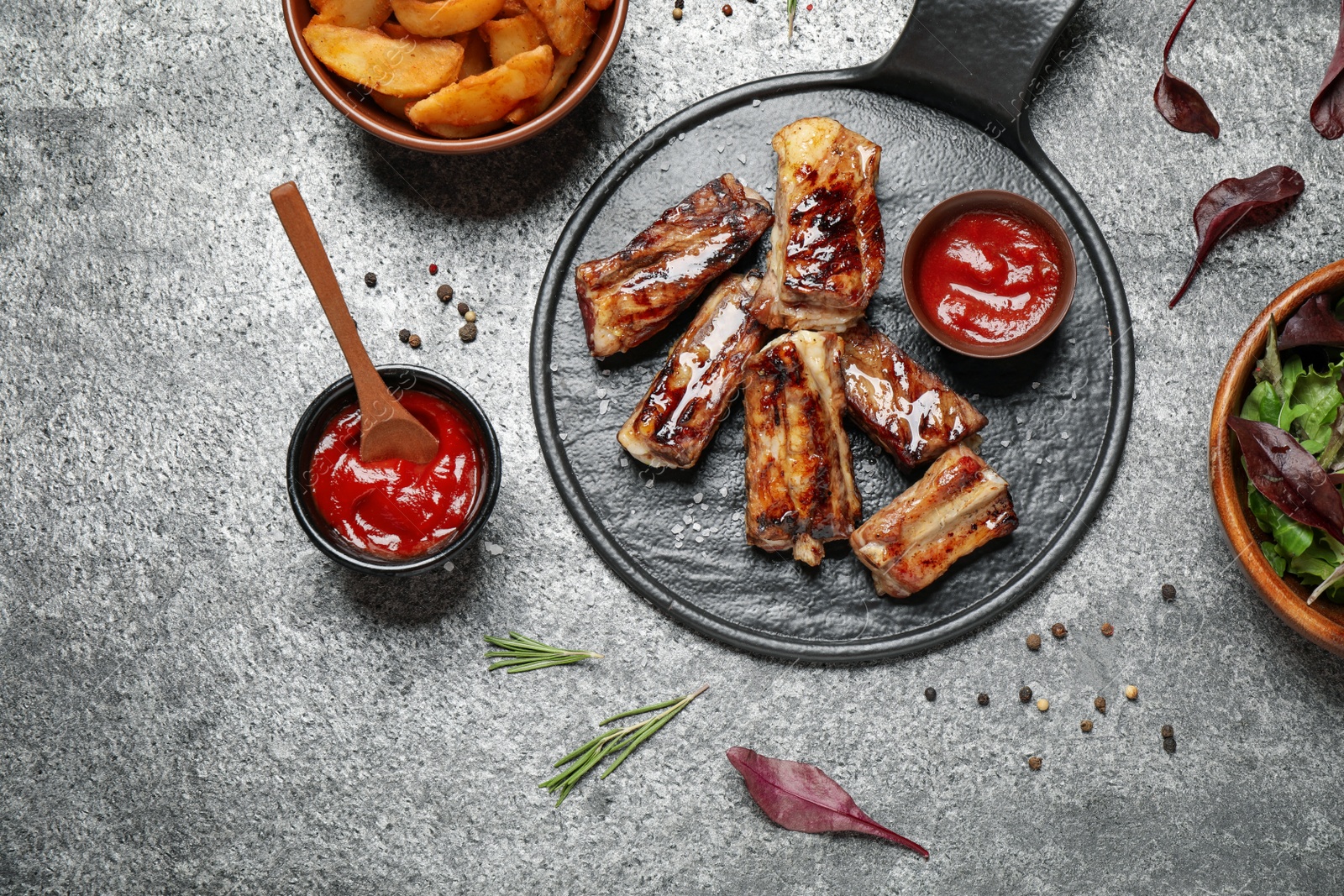 Photo of Delicious ribs on grey table, flat lay