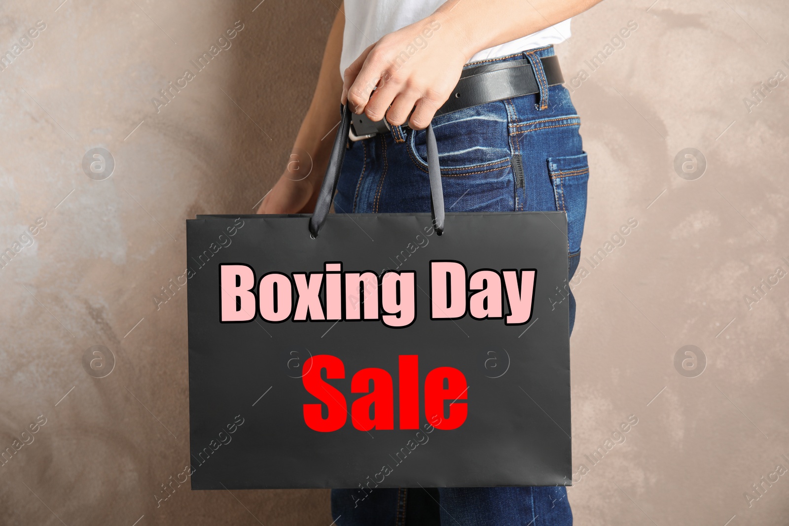 Image of Boxing day sale. Man with shopping bag on beige background, closeup