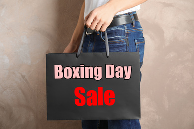 Image of Boxing day sale. Man with shopping bag on beige background, closeup