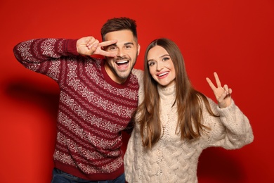 Photo of Couple wearing Christmas sweaters on red background