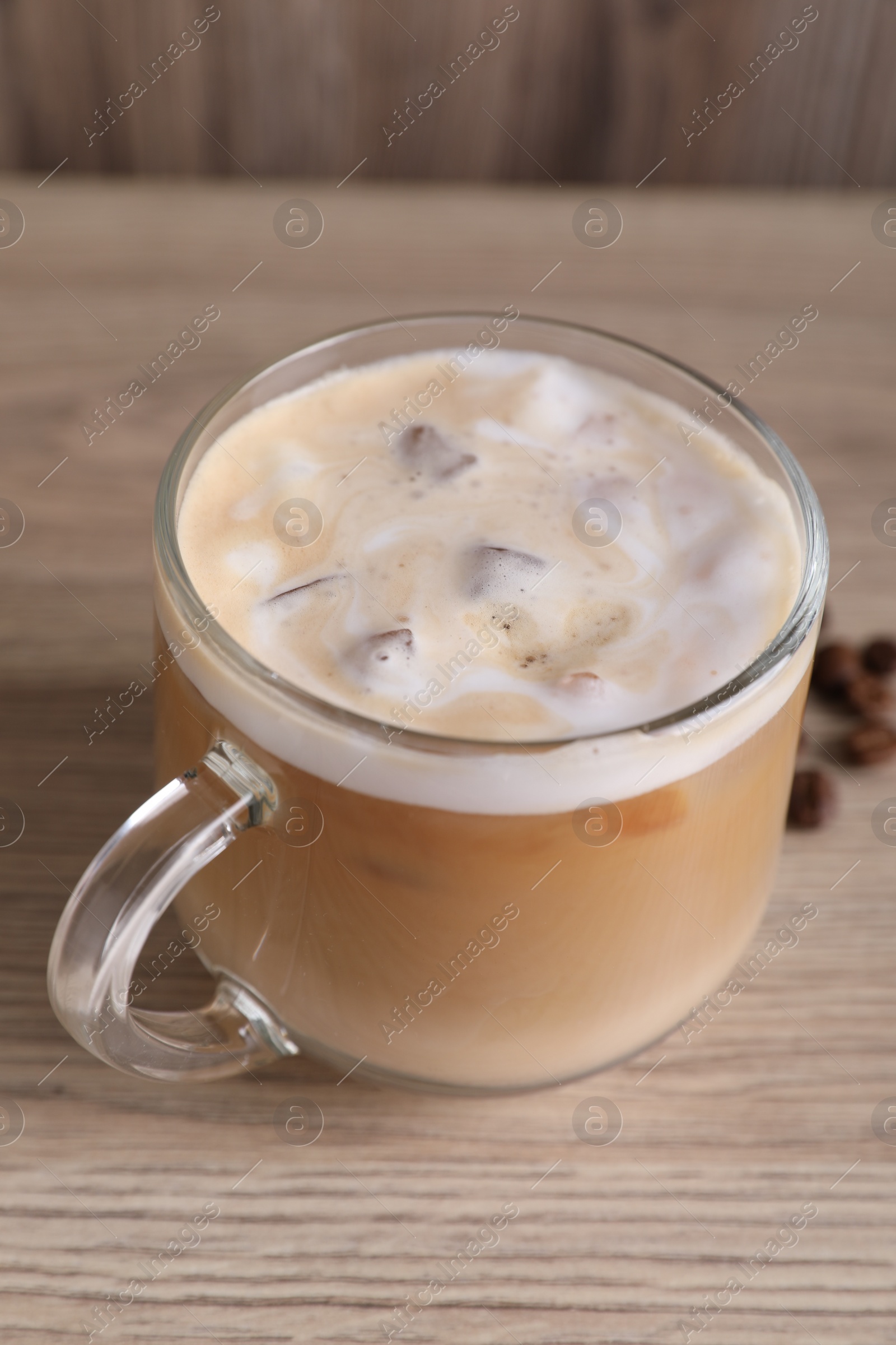 Photo of Cup of fresh iced coffee and beans on wooden table, closeup