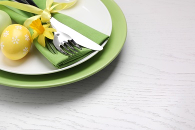 Festive Easter table setting with eggs on white wooden background, closeup. Space for text