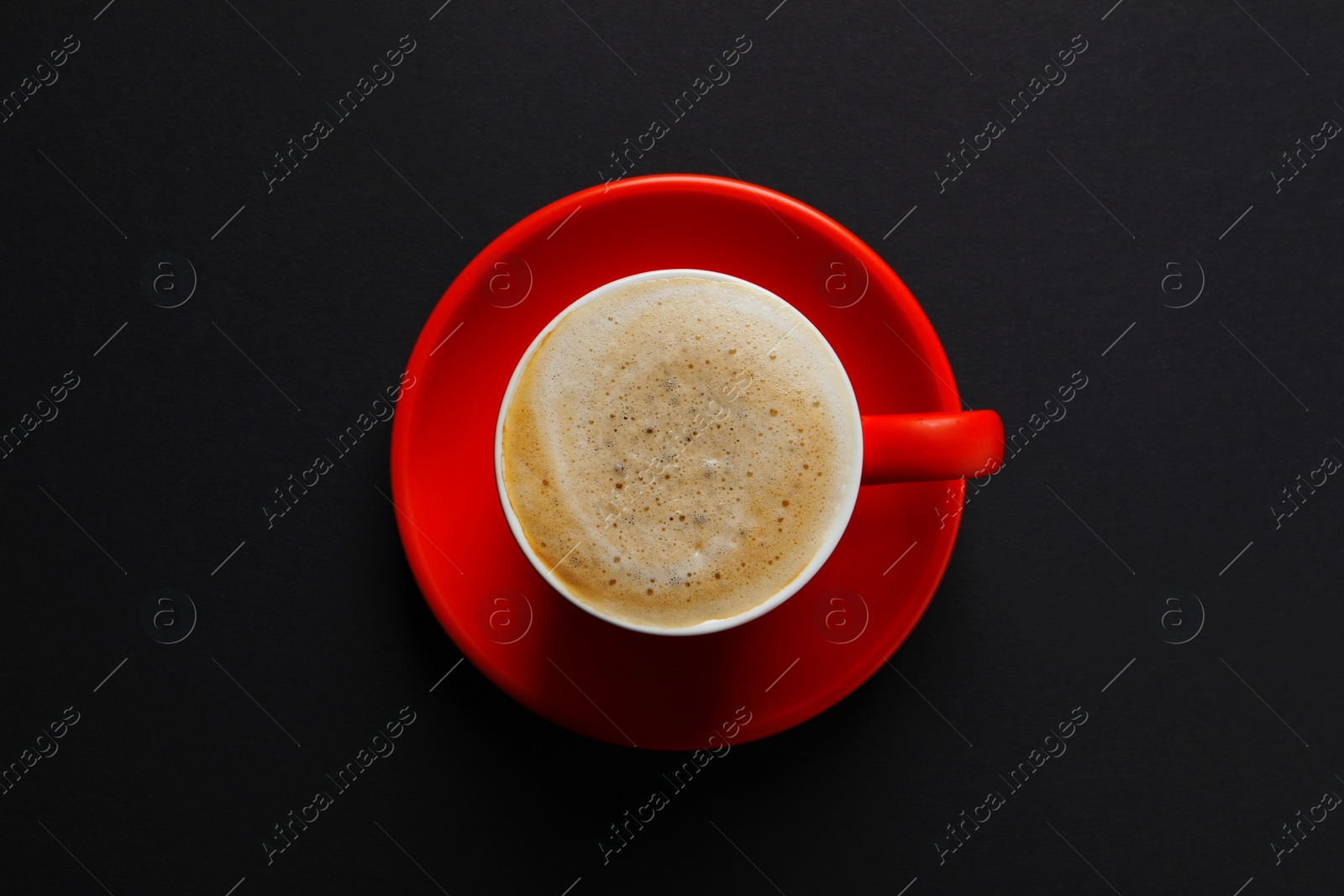 Photo of Red cup with aromatic cappuccino on black background, top view