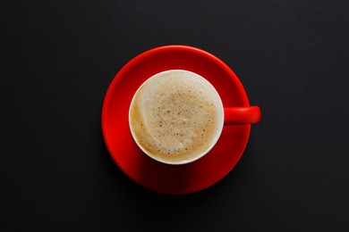 Photo of Red cup with aromatic cappuccino on black background, top view