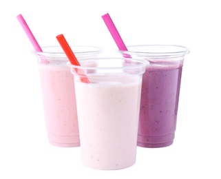 Photo of Tasty fresh milk shakes in plastic cups on white background