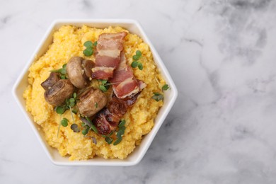 Photo of Cooked cornmeal with bacon, mushrooms and microgreens in bowl on white marble table, top view. Space for text