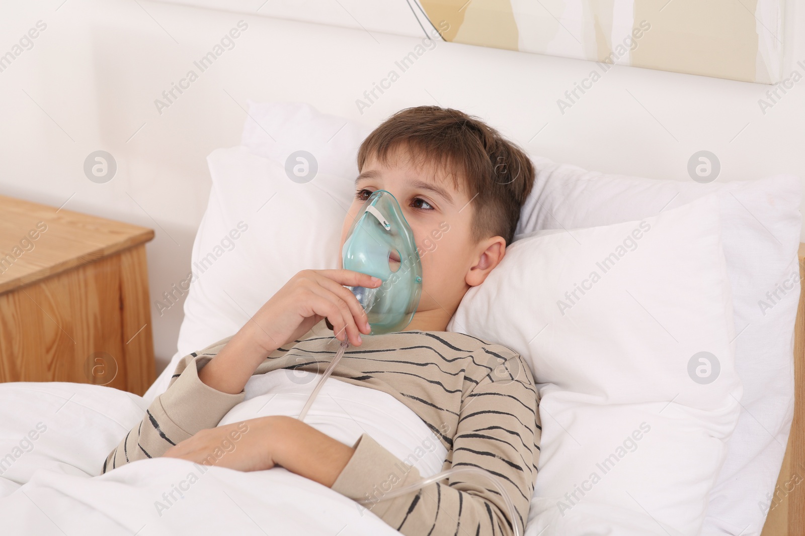 Photo of Boy using nebulizer for inhalation on bed at home