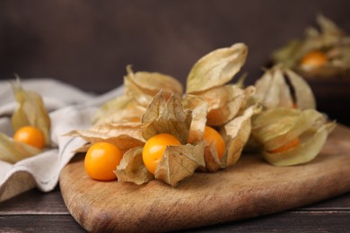 Ripe physalis fruits with calyxes on wooden table, closeup