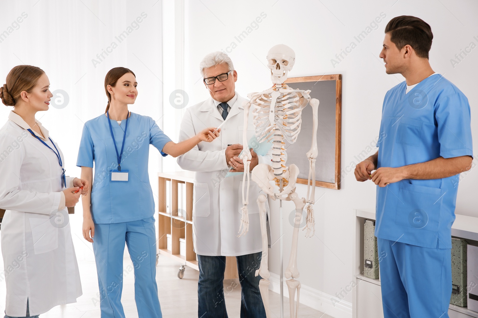 Photo of Medical students and professor studying human skeleton anatomy in classroom