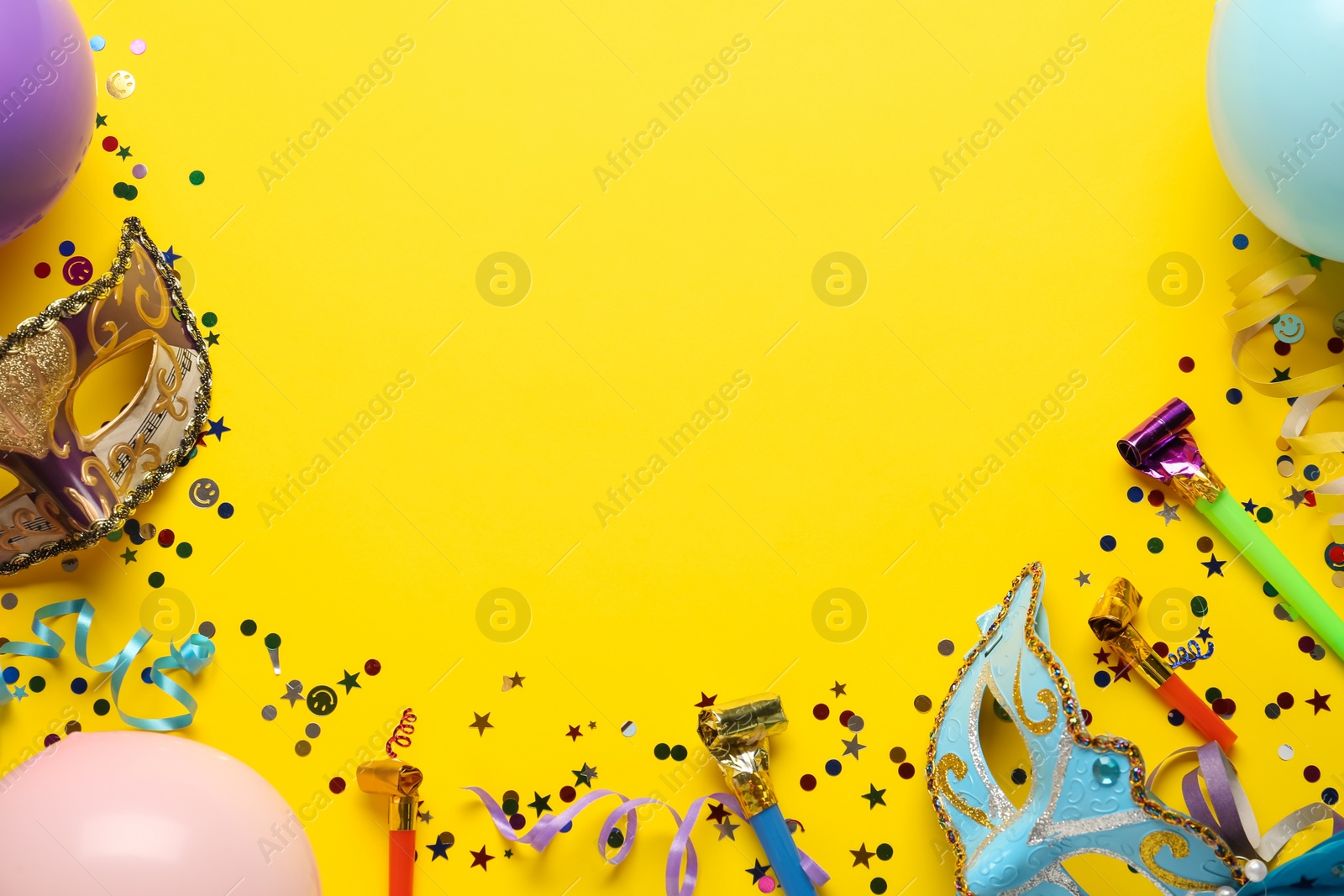 Photo of Beautiful carnival masks and party decor on yellow background, flat lay. Space for text