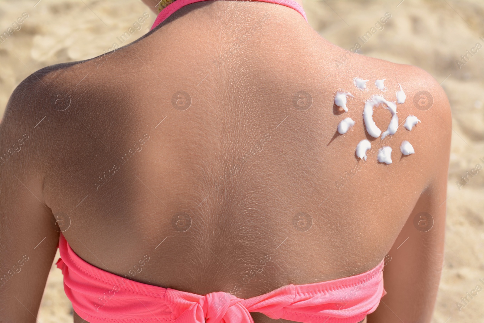 Photo of Little girl with sun protection cream on body outdoors, closeup