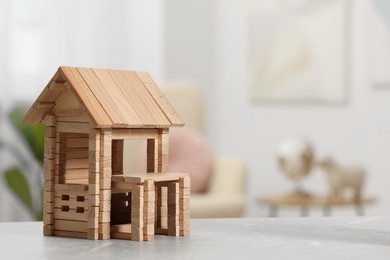 Photo of Wooden house on light grey table indoors, closeup. Space for text. Children's toy