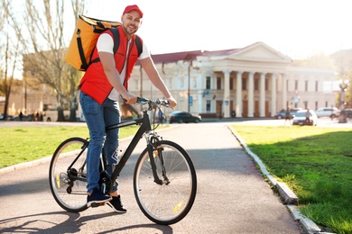 Photo of Male courier on bicycle delivering food in city