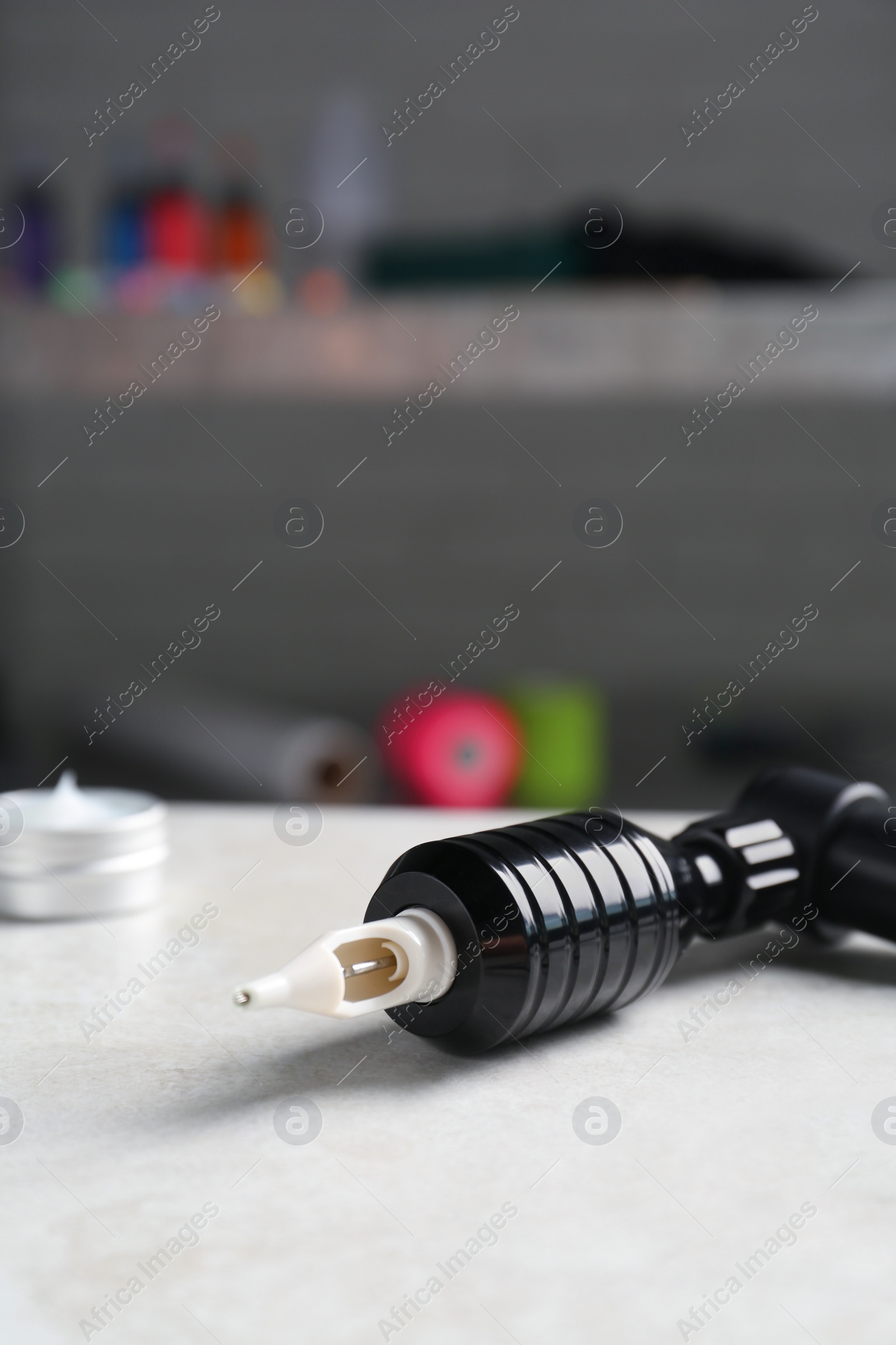 Photo of Modern professional tattoo machine on white table in salon