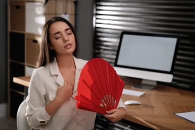 Photo of Woman with hand fan suffering from heat at home. Summer season