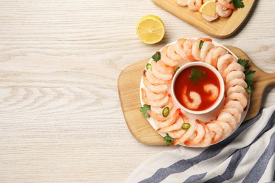 Tasty boiled shrimps with cocktail sauce, chili and parsley on light wooden table, top view. Space for text