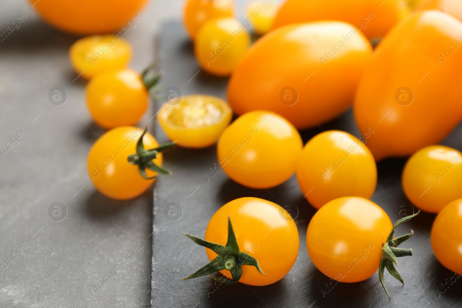 Photo of Ripe yellow tomatoes on grey table, closeup