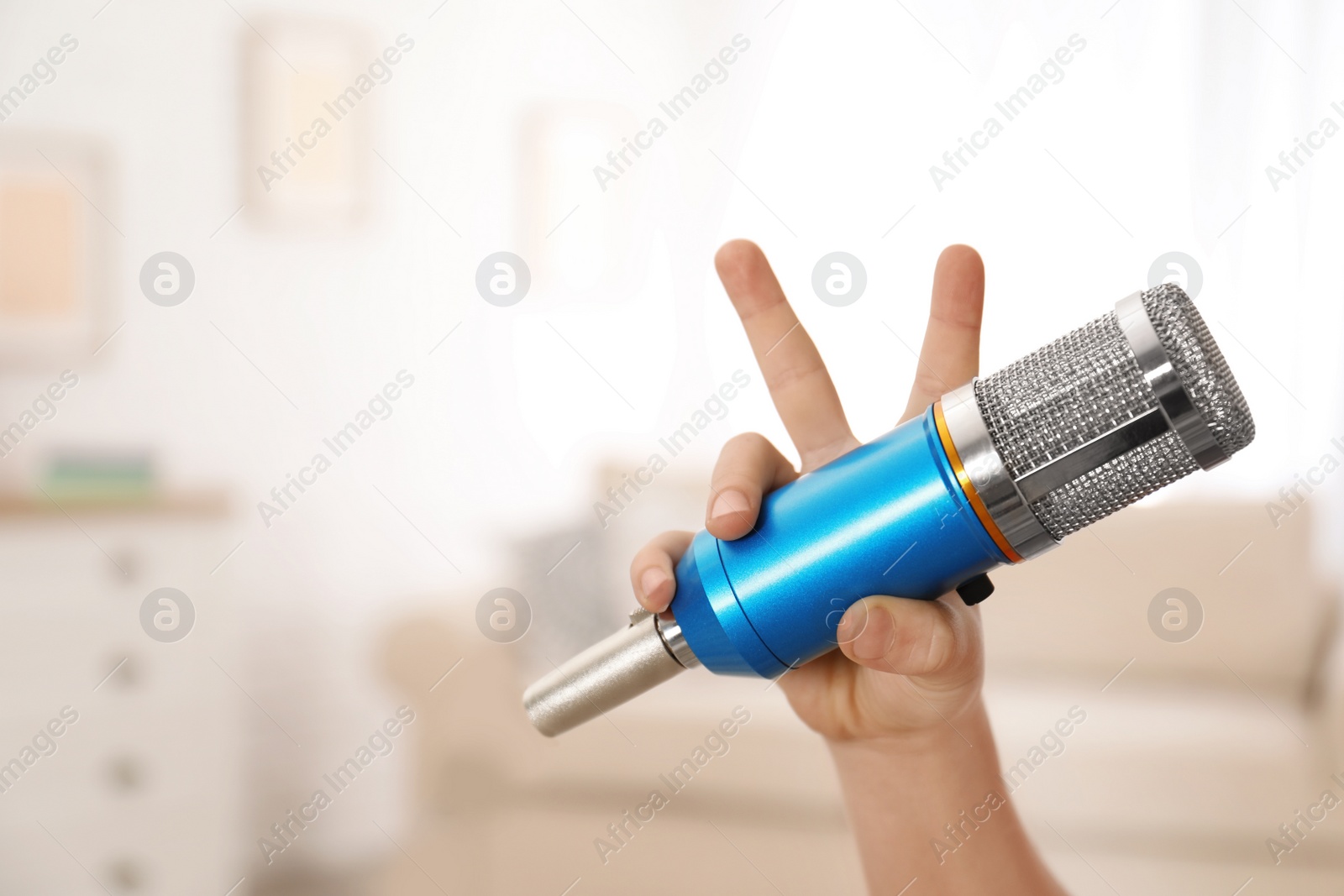 Photo of Child holding microphone at home, closeup of hand