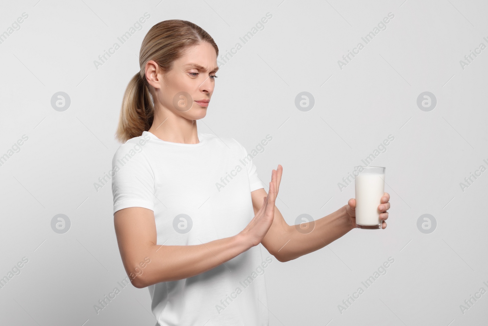 Photo of Woman with glass of milk suffering from lactose intolerance on white background