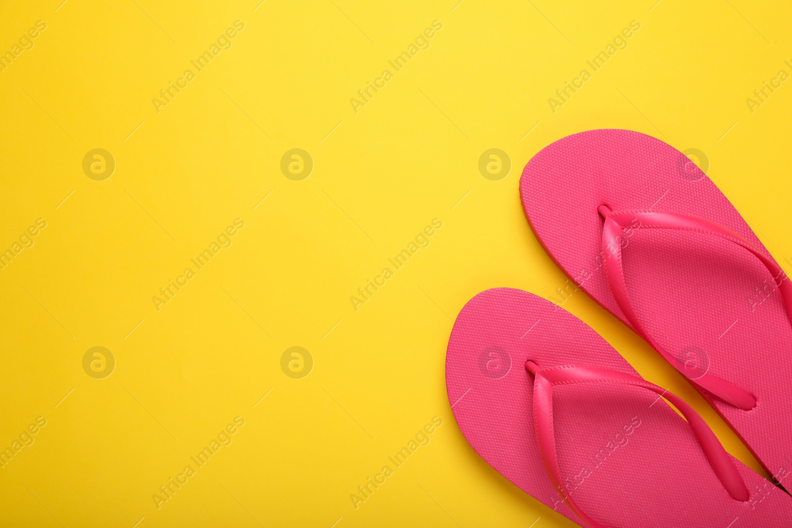 Photo of Stylish pink flip flops on yellow background, top view. Space for text