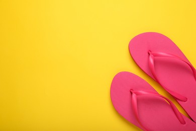 Photo of Stylish pink flip flops on yellow background, top view. Space for text