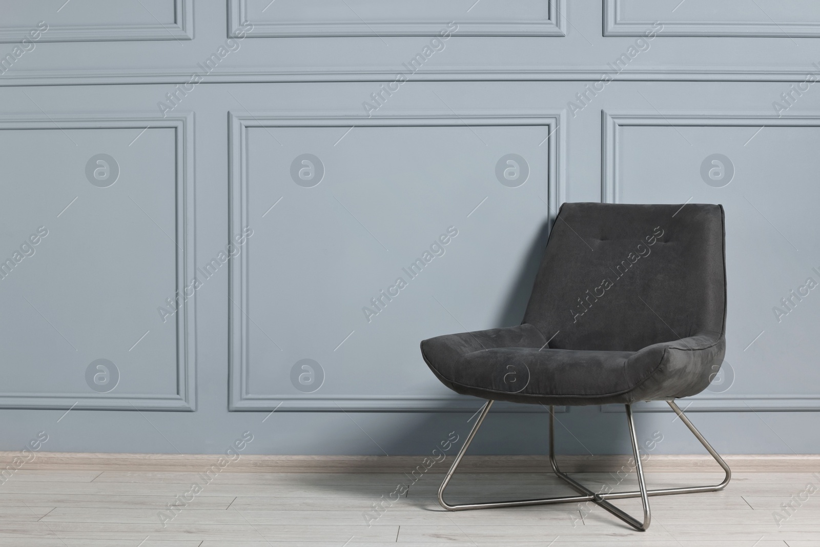 Photo of Comfortable armchair near grey wall in room, space for text