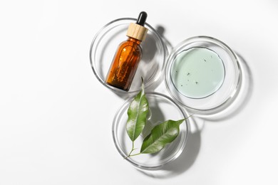 Photo of Petri dishes with sample, leaves and bottle on white background, top view