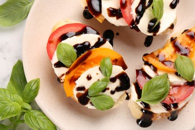 Photo of Delicious bruschettas with mozzarella cheese, tomatoes, balsamic vinegar and basil on table, closeup