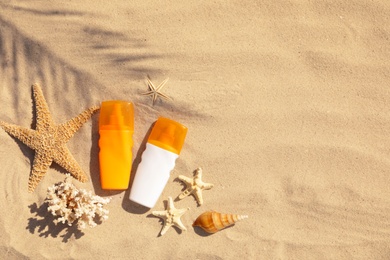 Photo of Flat lay composition with bottles of sunblock on sandy beach. Space for text