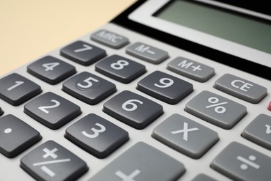 Calculator on beige background, closeup. Office equipment