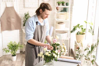 Photo of Male florist creating floral composition at workplace