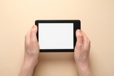 Photo of Woman using e-book reader on beige background, top view