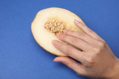 Photo of Young woman touching half of melon on blue background, above view. Sex concept